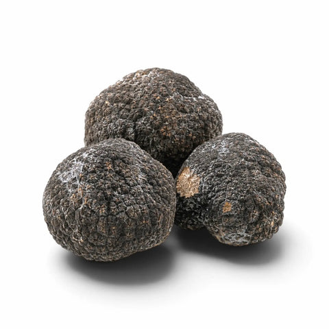 Tre tartufi interi congelati con una leggera brina naturale su sfondo bianco