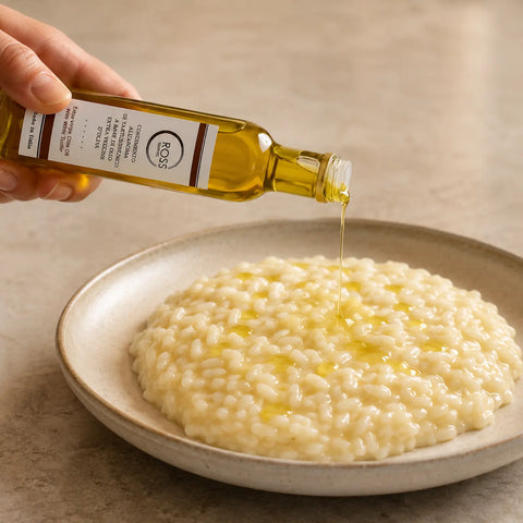 Olio d’oliva al tartufo bianco versato a filo su un risotto caldo e cremoso
